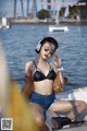 A woman in a black bikini sitting on a boat.