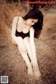 A woman in a black lingerie sitting on a pile of hay.