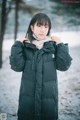 A woman wearing a black coat standing in the snow.