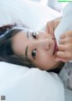 A woman laying in bed with a tissue in her mouth.