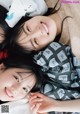 A couple of young women laying on top of a bed.