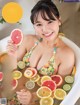 A woman in a bathtub holding a slice of grapefruit.