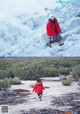 A woman in a red jacket and a little girl in a blue dress.