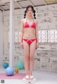 A woman in a red bikini standing on a scale.