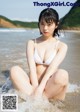 A woman in a white bikini sitting in the water.