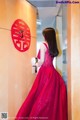 A woman in a red dress standing in front of a door.