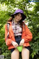 A woman in an orange jacket and a purple hat posing for a picture.