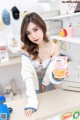 A woman sitting at a counter holding a cup of ice cream.