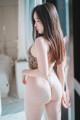 A woman standing in front of a mirror in a lingerie.