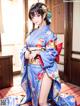 A woman in a blue kimono sitting on a red rug.