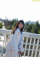 A woman in a white coat standing on a bridge.