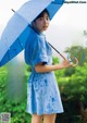 A woman in a blue dress holding an umbrella.